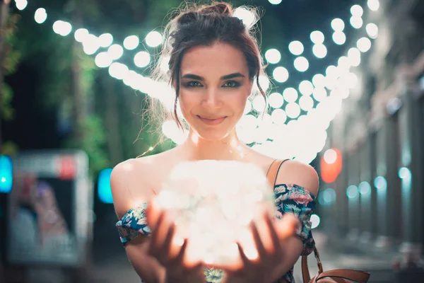 Hermosa joven mujer sonriendo y hablando guirnaldas de luces en la ciudad — Foto de Stock