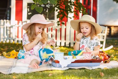 Yeşil çimenlerin üzerinde oturan iki küçük kız