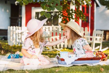 Yeşil çimenlerin üzerinde oturan iki küçük kız