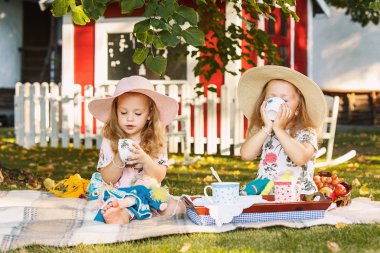 Yeşil çimenlerin üzerinde oturan iki küçük kız