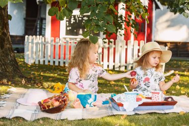 Yeşil çimenlerin üzerinde oturan iki küçük kız