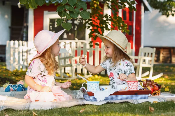 Yeşil çimenlerin üzerinde oturan iki küçük kız