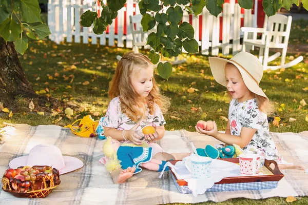 Two little girls sitting on green grass