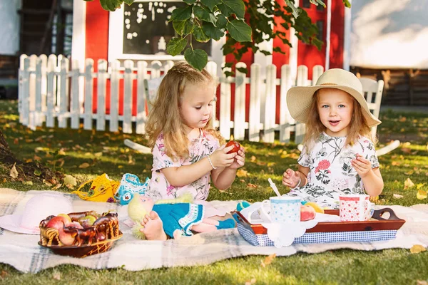 Yeşil çimenlerin üzerinde oturan iki küçük kız