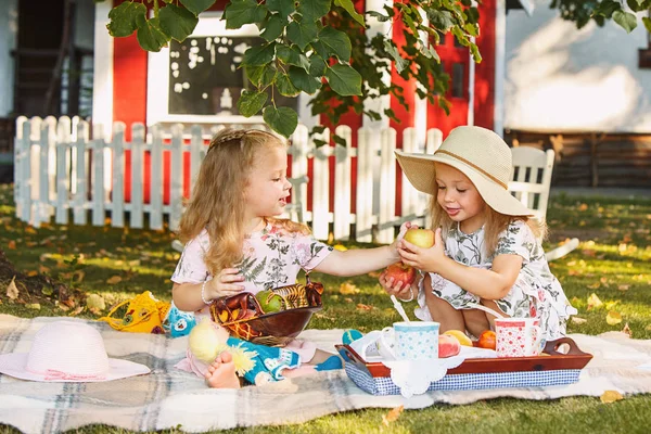 Two little girls sitting on green grass