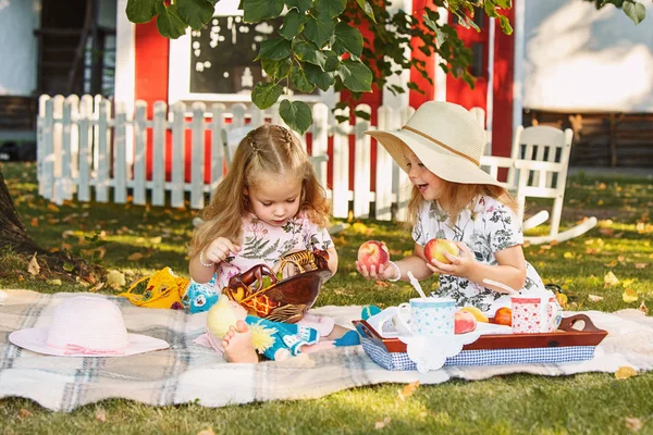 Yeşil çimenlerin üzerinde oturan iki küçük kız