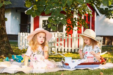 Yeşil çimenlerin üzerinde oturan iki küçük kız