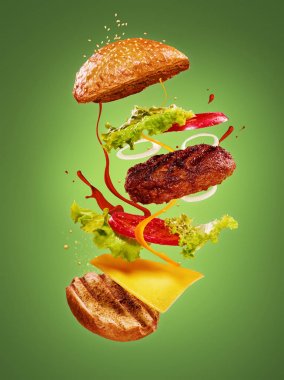 Maddeler yeşil arka plan üzerinde uçan ile hamburger