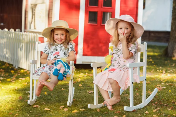 Meninas loiras bonitos em chapéus sentados no campo com brinquedos macios no verão . — Fotografia de Stock