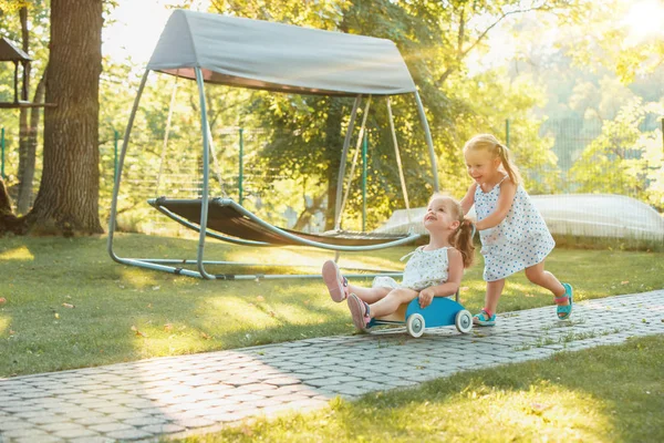 Meninas loiras bonitos montando um carro de brinquedo no verão . — Fotografia de Stock