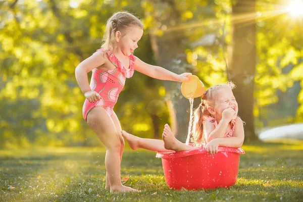 Ładny mały blond dziewczyny gry z wodą rozpryskową na polu latem — Zdjęcie stockowe