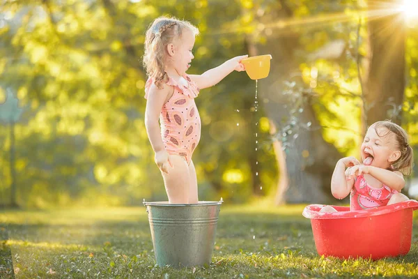 Ładny mały blond dziewczyny gry z wodą rozpryskową na polu latem — Zdjęcie stockowe