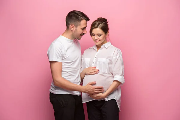 Bonito homem está ouvindo sua bela mulher grávida barriga e sorrindo — Fotografia de Stock