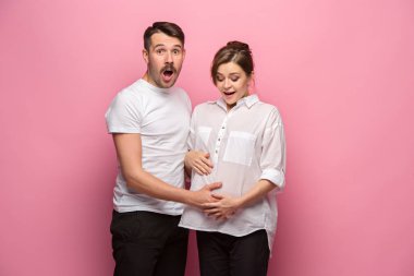 Yakışıklı adam güzel hamile karısının karnını dinliyor ve gülümsüyor.