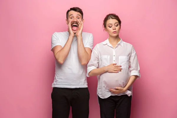 Смішний здивований красивий чоловік і його красиві вагітні дружини животик — стокове фото