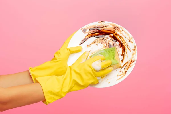 Händer i gula skyddshandskar tvätt en tallrik — Stockfoto