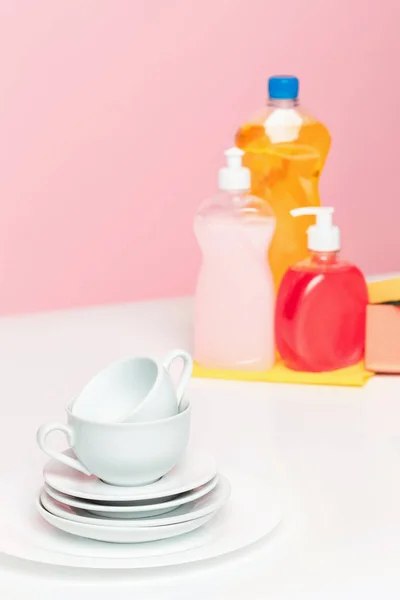 Кілька тарілок, кухонні губки та пластикові пляшки з натуральним милом для посуду, що використовується для ручної посудомийки . — стокове фото