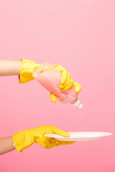 Händer i gula skyddshandskar tvätt en tallrik — Stockfoto