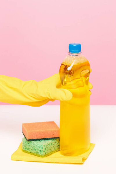 The womans hand cleaning on a pink background. Cleaning or housekeeping concept