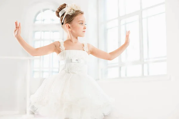 Uma bailarina em tutu. Adorável criança dançando balé clássico em um estúdio branco . — Fotografia de Stock