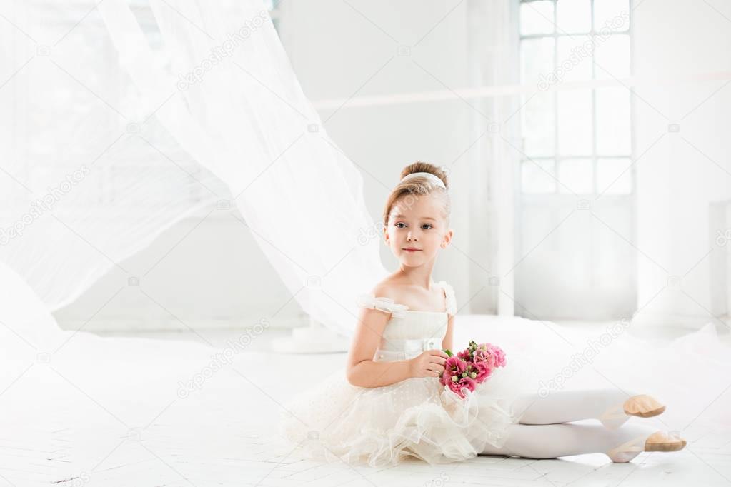 The little balerina in white tutu in class at the ballet school