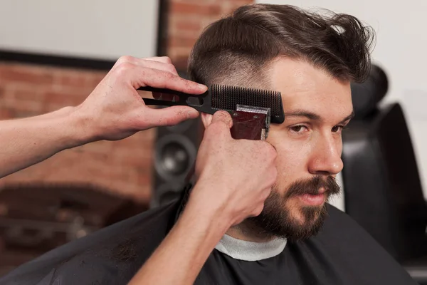 Händerna på Frisör gör frisyr till ung man i barbershop — Stockfoto