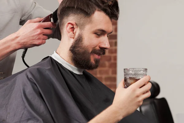 Las manos de peluquero haciendo corte de pelo a un joven en la barbería —  Fotos de Stock