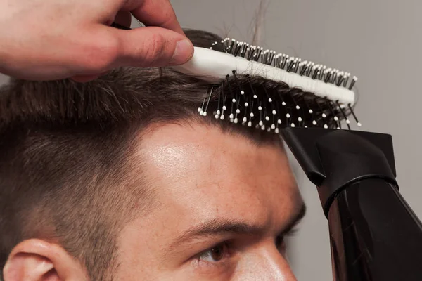 Die Hände des Friseurs, der einem jungen Mann im Friseursalon die Haare schneidet — Stockfoto