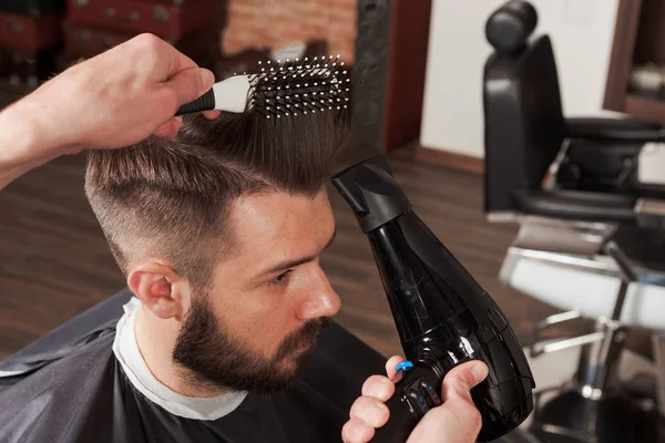 Las manos de peluquero haciendo corte de pelo a un joven en la barbería — Foto de Stock