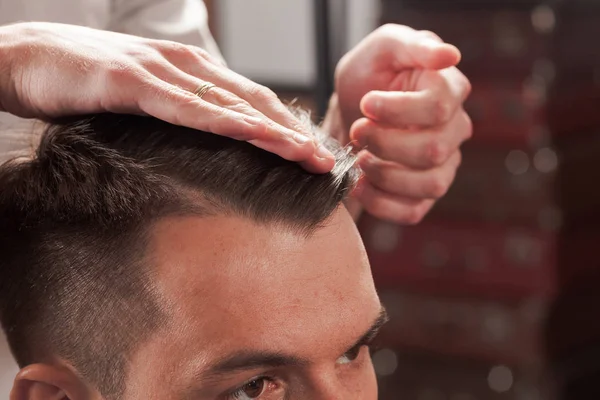 Las manos de peluquero haciendo corte de pelo a un joven en la barbería — Foto de Stock