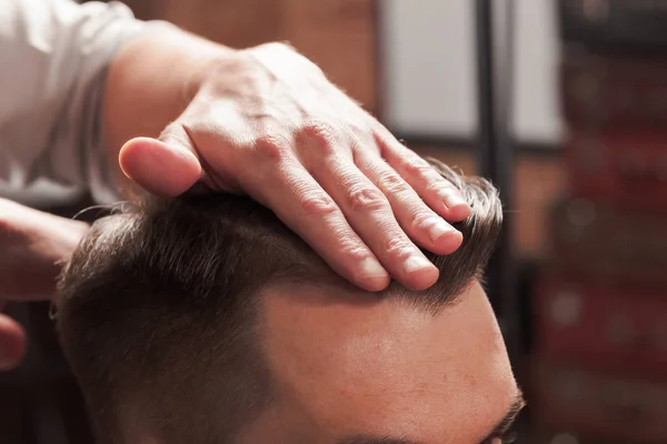 Las manos de peluquero haciendo corte de pelo a un joven en la barbería — Foto de Stock
