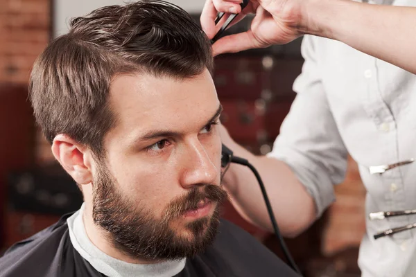 Las manos de peluquero haciendo corte de pelo a un joven en la barbería — Foto de Stock