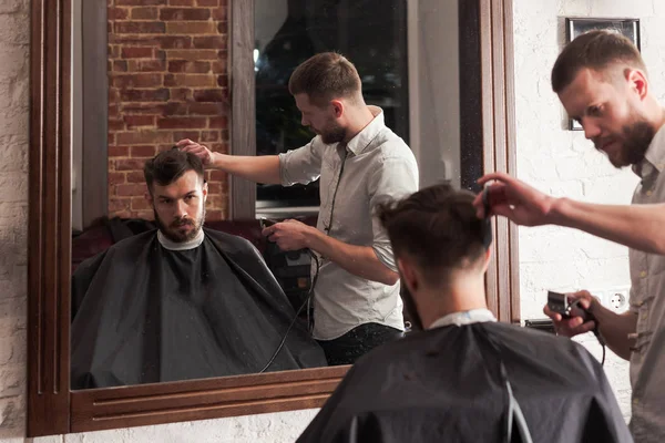 Genç yakışıklı Kuaför berber içinde çekici adamın saç kesimi yapma