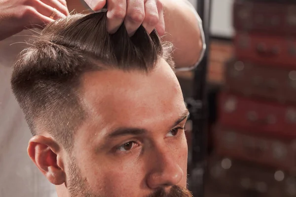 Las manos de peluquero haciendo corte de pelo a un joven en la barbería — Foto de Stock