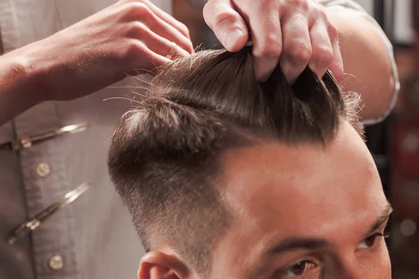 Las manos de peluquero haciendo corte de pelo a un joven en la barbería — Foto de Stock