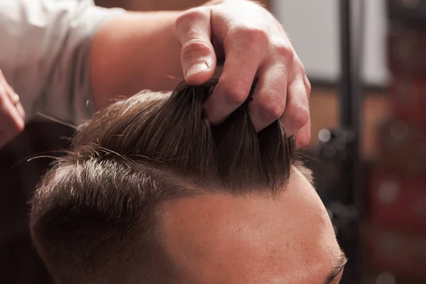 Les mains de coiffeur faisant coupe de cheveux au jeune homme dans le salon de coiffure — Photo