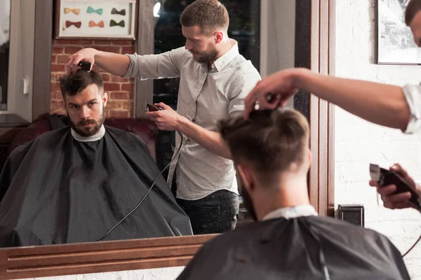 Ung snygg frisör att göra frisyr av attraktiv man i barbershop — Stockfoto