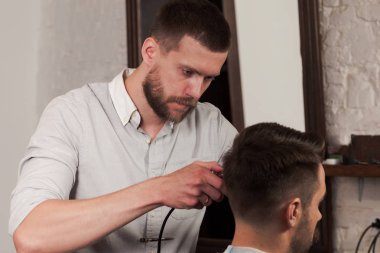 Genç yakışıklı Kuaför berber içinde çekici adamın saç kesimi yapma