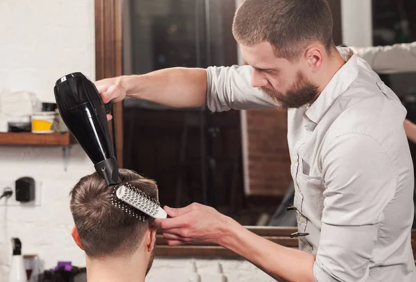 Jovem barbeiro bonito fazendo corte de cabelo de homem atraente na barbearia — Fotografia de Stock