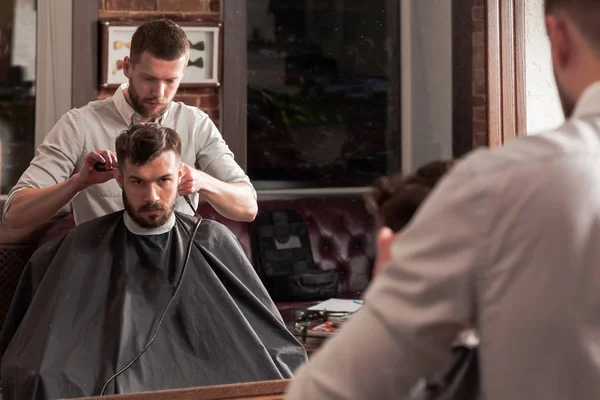 Joven peluquero guapo haciendo corte de pelo de hombre atractivo en la barbería — Foto de Stock