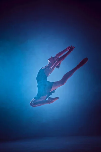 Красивая молодая балерина, прыгающая на сиреневом фоне . — стоковое фото
