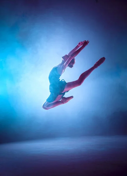 Красивая молодая балерина, прыгающая на сиреневом фоне . — стоковое фото