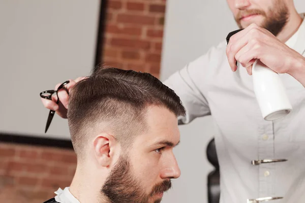 Giovane bel barbiere che fa taglio di capelli di uomo attraente in barbiere — Foto Stock