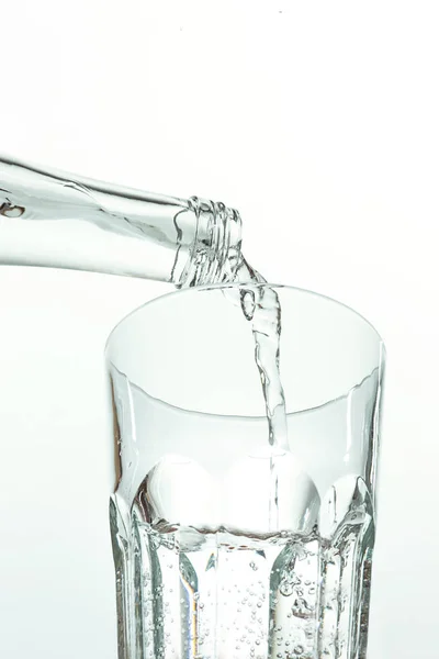 Verter el agua de la botella en un vaso sobre blanco —  Fotos de Stock