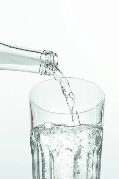 Ρίχνει νερό από το μπουκάλι στο ποτήρι σε λευκό — Φωτογραφία Αρχείου
