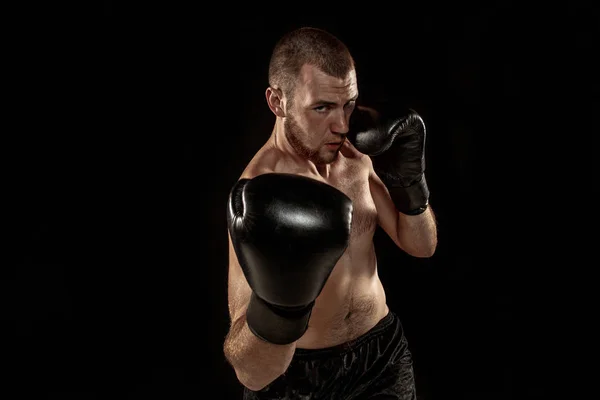 Der junge Mann kickboxt auf schwarz — Stockfoto