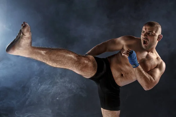 The young man kickboxing on black — Stock Photo, Image