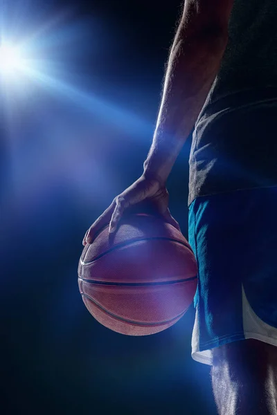 The portrait of a basketball player with a ball against dark studio background. advertising concept
