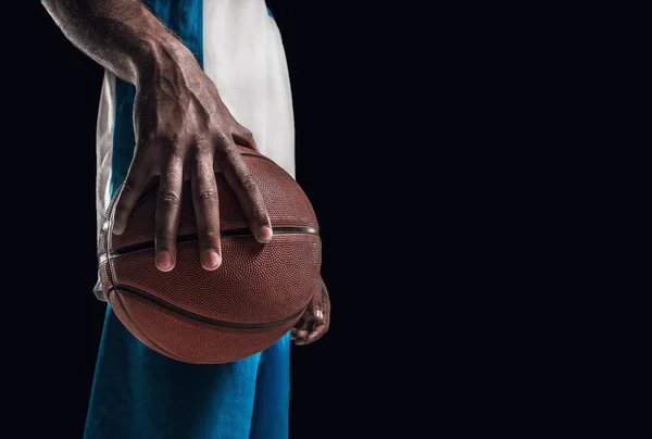 一个球在黑暗摄影棚背景下的篮球运动员之手 广告的概念 — 图库照片