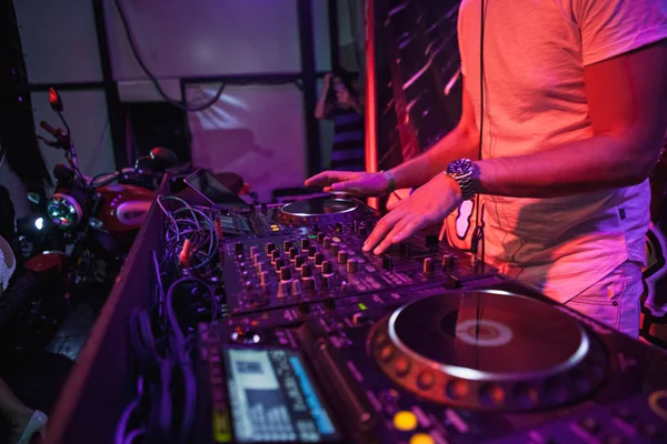 DJ tocando música en el mezclador sobre fondo borroso colorido — Foto de Stock